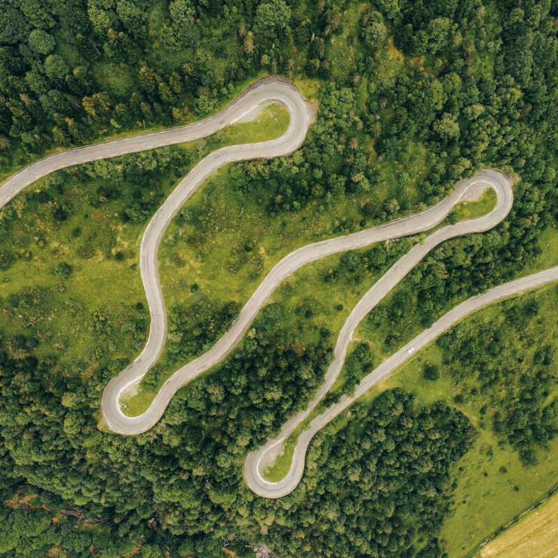 An overhead photo of a road winding through a forest